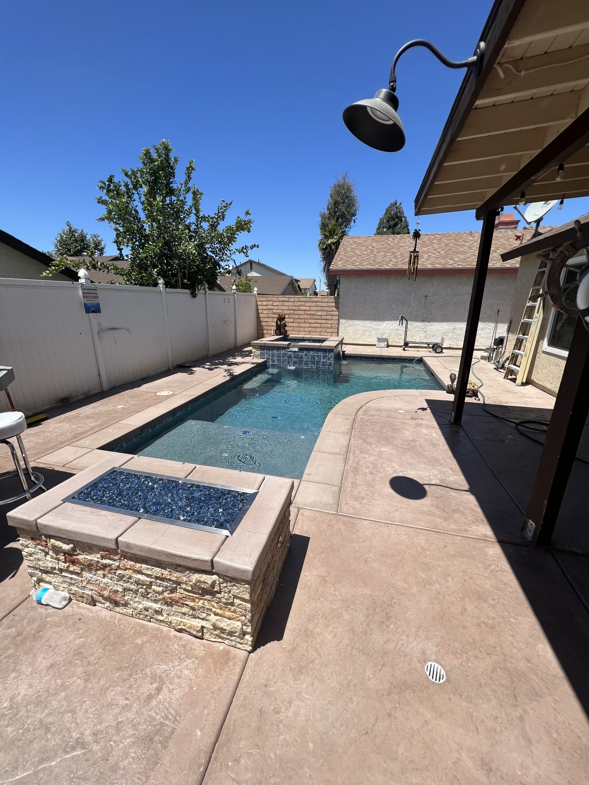 Custom backyard pool with raised spa, spillway water feature, and stamped concrete decking designed for modern outdoor living.