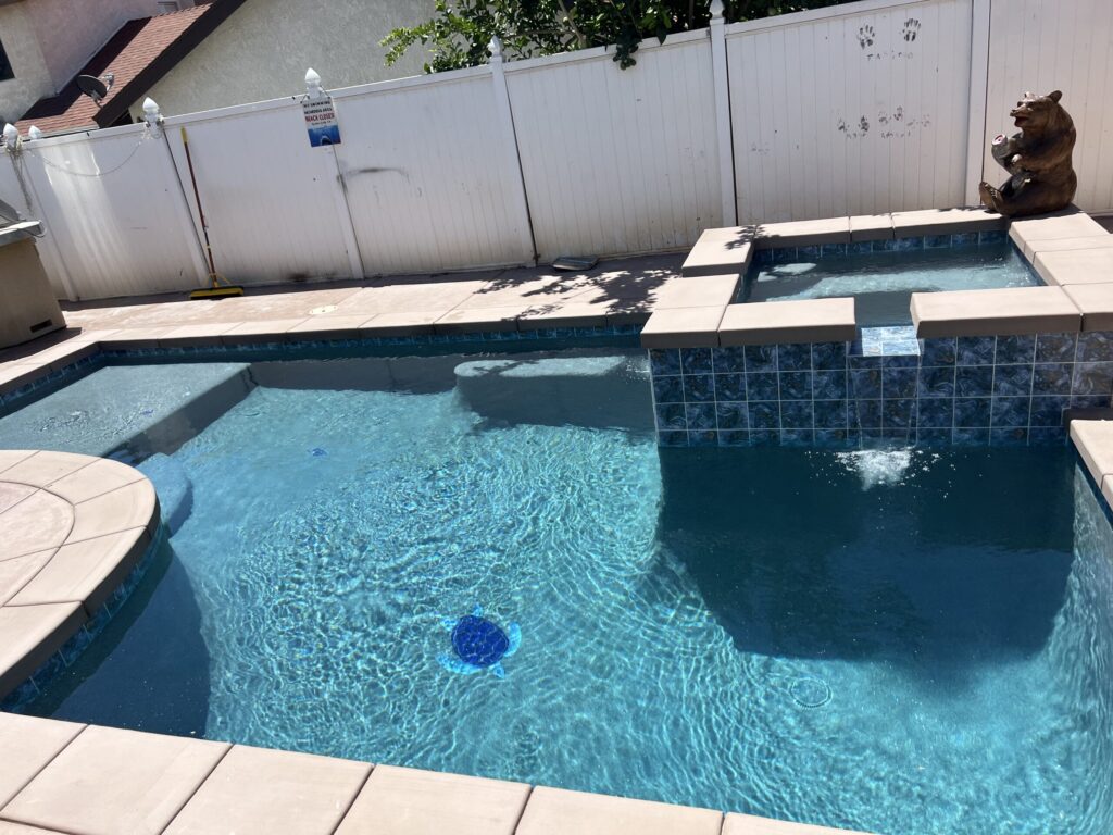 Custom backyard swimming pool with raised spa, clear blue water, and clean modern hardscape creating a private outdoor retreat.