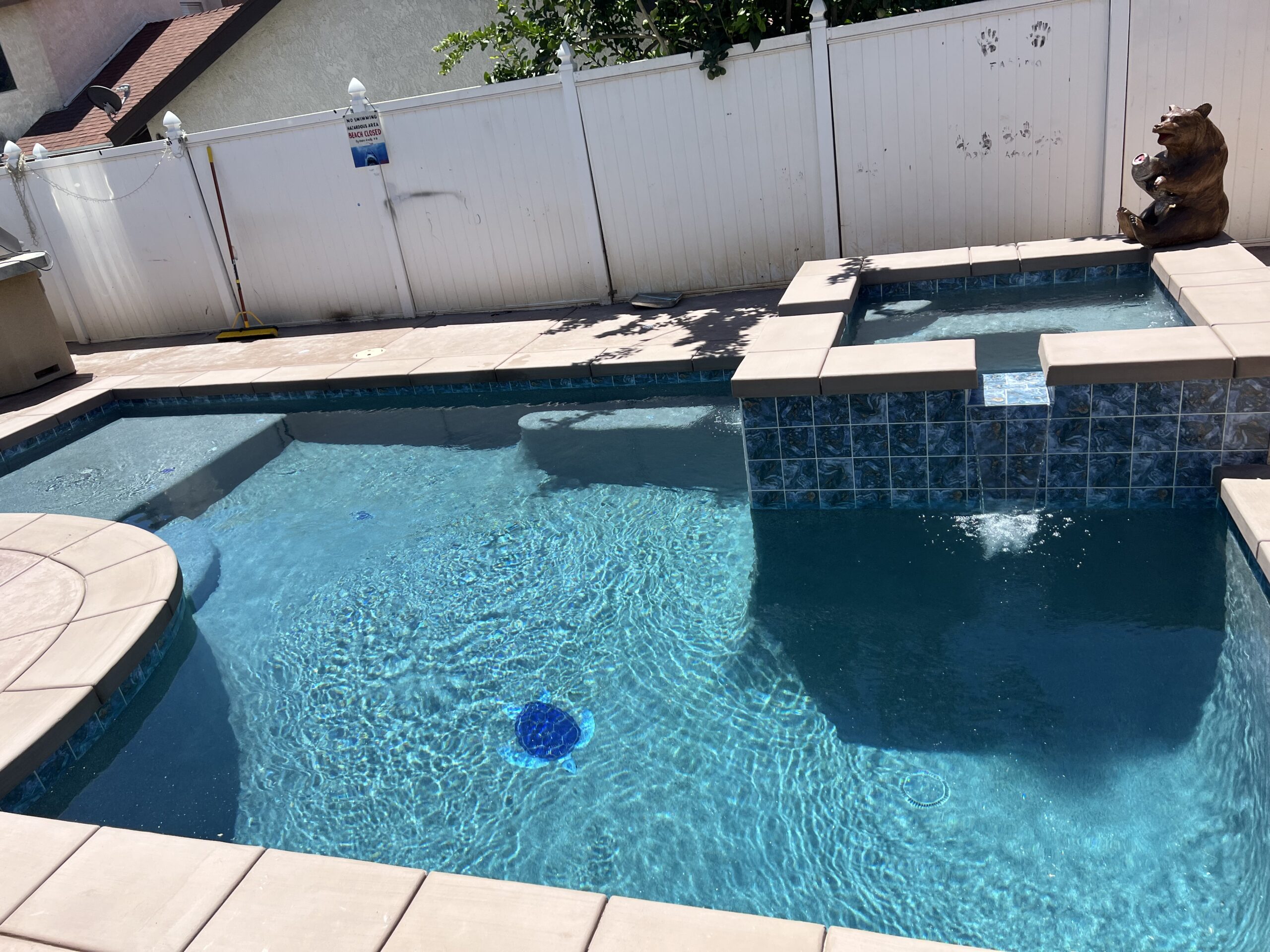 Custom backyard swimming pool with raised spa, clear blue water, and clean modern hardscape creating a private outdoor retreat.